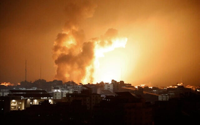 Le feu et la fumée s’élevant au-dessus des bâtiments lors d'une frappe aérienne israélienne dans la ville de Gaza, le 8 octobre 2023. (Crédit : Eyad Baba/AFP)