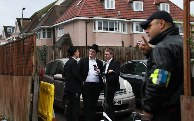 Un agent de sécurité devant une synagogue du nord de Londres, le 13 octobre 2023, après que le gouvernement britannique a annoncé un financement supplémentaire pour la protection des lieux juifs. (Crédit : Daniel LEAL / AFP) Un agent de sécurité devant une synagogue du nord de Londres, le 13 octobre 2023, après que le gouvernement britannique a annoncé un financement supplémentaire pour la protection des lieux juifs. (Crédit : Daniel LEAL / AFP)