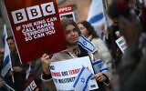 Illustration : Des manifestants brandissant des pancartes et des drapeaux d'Israël, appelant la BBC (British Broadcasting Corporation) à qualifier le Hamas de « terroriste », devant le siège de la chaîne, à Londres, le 16 octobre 2023. (Crédit : Daniel Leal/AFP)