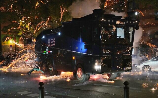 Des pétards explosent près d'une voiture de police lors d'une manifestation pro-palestinienne à Berlin, le 18 octobre 2023. (Crédit : Zakaria ABDELKAFI / AFP)