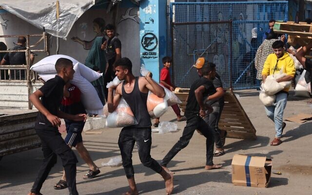 Des Palestiniens collectent des sacs de légumes secs dans un centre d'approvisionnement géré par l'ONU, distribuant de la nourriture aux Palestiniens locaux et aux personnes déplacées à la suite de l'appel d'Israël à plus d'un million de résidents du nord de Gaza à se déplacer vers le sud pour leur sécurité, à Deir al-Balah le 28 octobre 2023, dans le cadre des batailles en cours entre Israël et le Hamas. (Crédit : MOHAMMED ABED / AFP)