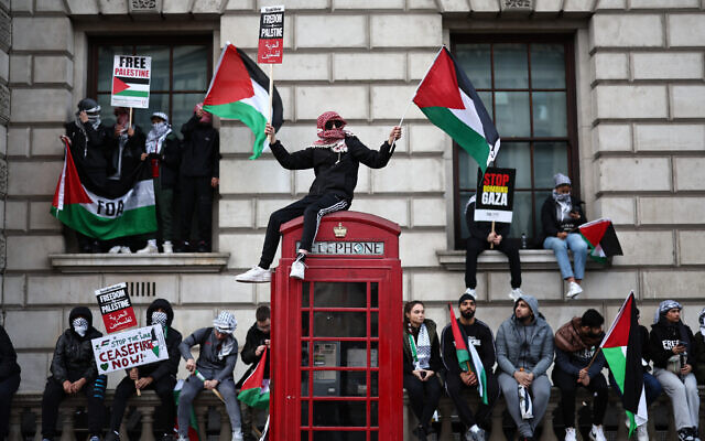 Des manifestants brandissant des pancartes et des drapeaux palestiniens lors d'une "Marche pour la Palestine" pour demander un cessez-le-feu dans la guerre entre Israël et le Hamas, à Londres, le 28 octobre 2023. (Crédit : Henry Nicholls/AFP)