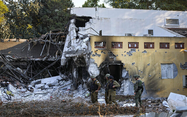 Des soldats israéliens passant devant des maisons détruites par des terroristes du Hamas dans le kibboutz Beeri, le 14 octobre 2023. (Crédit : Ariel Schalit/AP)