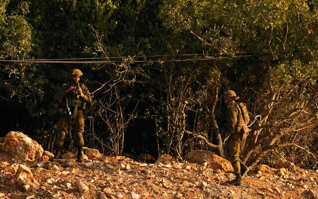 Des soldats israéliens prenant position le long du mur et de la clôture de la frontière avec le Liban, vus du côté libanais de la frontière israélo-libanaise dans le village de Marwaheen, au sud du Liban, le 12 octobre 2023. (Crédit : Hassan Ammar/AP Photo)