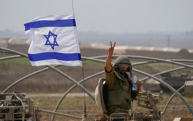 Un soldat israélien fait le signe de la victoire depuis un blindé qui se dirige vers la frontière avec la bande de Gaza, dans le sud d'Israël, le 14 octobre 2023. (Crédit : AP Photo/Ariel Schalit) Un soldat israélien fait le signe de la victoire depuis un blindé qui se dirige vers la frontière avec la bande de Gaza, dans le sud d'Israël, le 14 octobre 2023. (Crédit : AP Photo/Ariel Schalit)