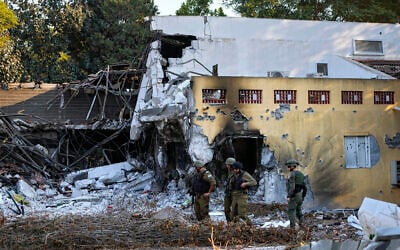 Des soldats israéliens passant devant des maisons détruites par des terroristes du Hamas dans le kibboutz Beeri, le 14 octobre 2023. (Crédit : Ariel Schalit/AP)
