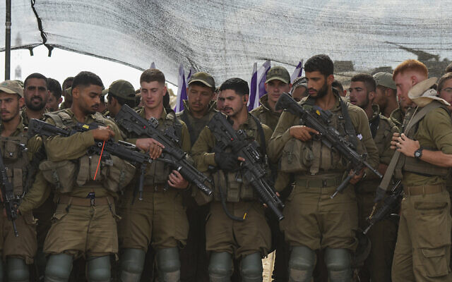 Des soldats israéliens écoutant le ministre de la Défense, Yoav Gallant, lors de sa visite d'une zone de transit près de la frontière avec la bande de Gaza, dans le sud d'Israël, le 19 octobre 2023. (Crédit : Tsafrir Abayov/AP Photo)