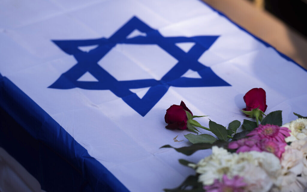 Des fleurs sur un cercueil drapé du drapeau israélien lors des funérailles de Dana Bachar et de son fils Carmel, au cimetière de Gan Shlomo, dans le centre d'Israël, le 24 octobre 2023. (Crédit : Petros Giannakouris/AP Photo) Des fleurs sur un cercueil drapé du drapeau israélien lors des funérailles de Dana Bachar et de son fils Carmel, au cimetière de Gan Shlomo, dans le centre d'Israël, le 24 octobre 2023. (Crédit : Petros Giannakouris/AP Photo)