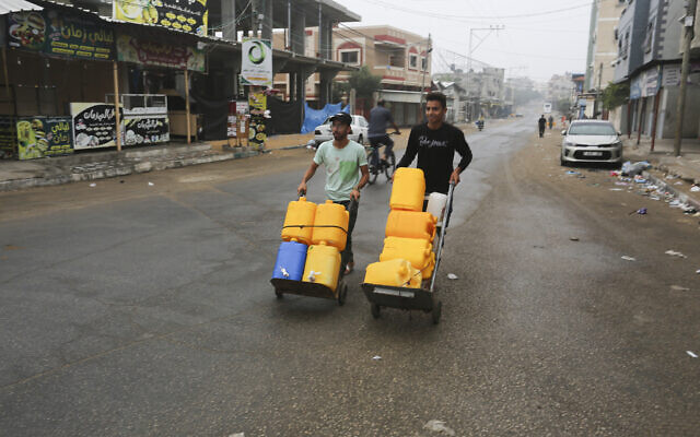 Des Palestiniens transportent des conteneurs à eau à Rafah, le 29 octobre 2023. (Crédit : AP/Hatem Ali) Des Palestiniens transportent des conteneurs à eau à Rafah, le 29 octobre 2023. (Crédit : AP/Hatem Ali)