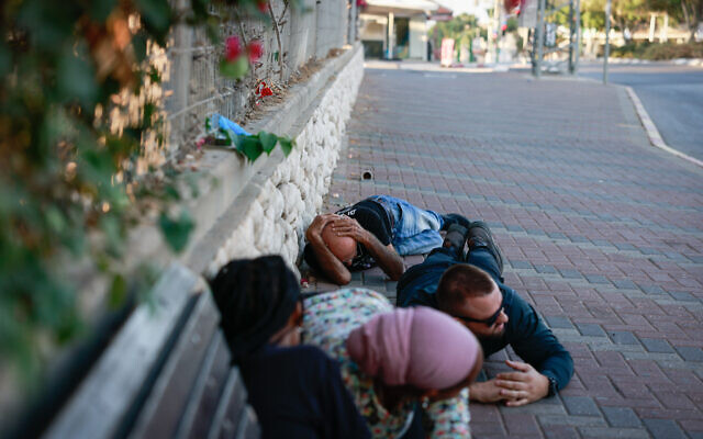 Des personnes se mettant à l'abri sur une route d'Ashkelon alors qu'une alerte à la roquette est déclenchée, le 10 octobre 2023. (Crédit : Chaïm Goldberg/Flash90) Des personnes se mettant à l'abri sur une route d'Ashkelon alors qu'une alerte à la roquette est déclenchée, le 10 octobre 2023. (Crédit : Chaïm Goldberg/Flash90)