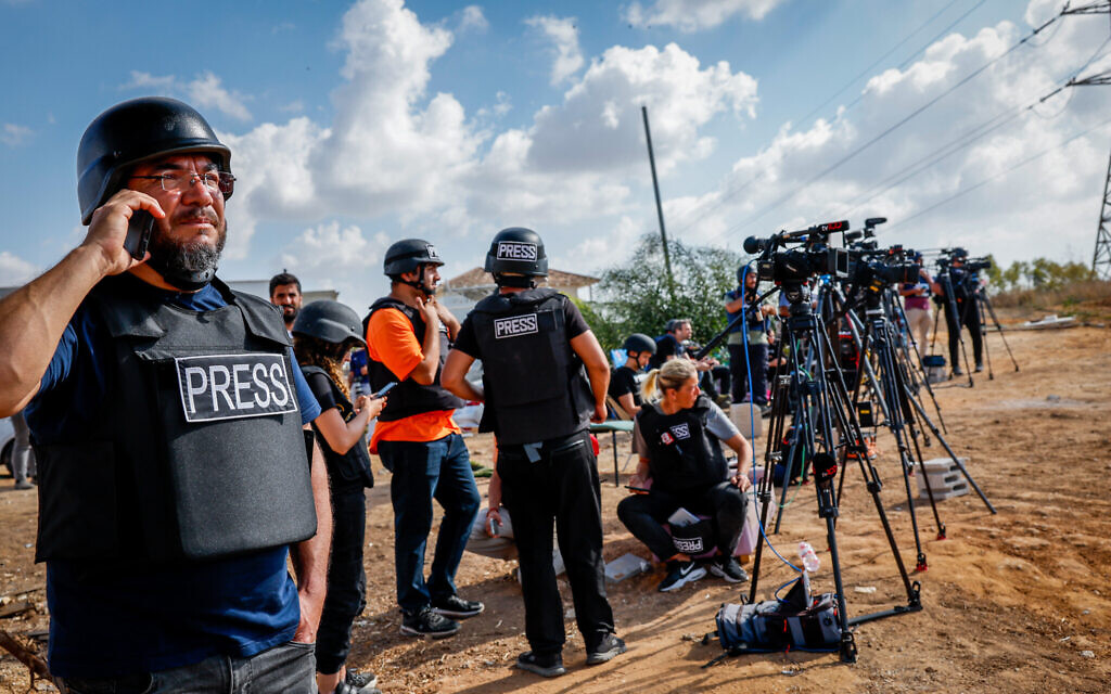 Des journalistes étrangers et israéliens se tenant sur une colline surplombant la bande de Gaza, dans la ville de Sderot, dans le sud d'Israël, le 19 octobre 2023. (Crédit : Nati Shohat/Flash90)
