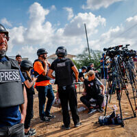 Des journalistes étrangers et israéliens se tenant sur une colline surplombant la bande de Gaza, dans la ville de Sderot, dans le sud d'Israël, le 19 octobre 2023. (Crédit : Nati Shohat/Flash90)