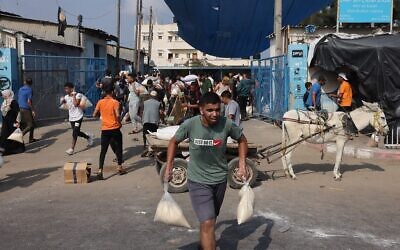 Des Palestiniens envahissent un centre d'approvisionnement humanitaire géré par l'ONU, qui distribue de la nourriture aux familles déplacées, suite à l'appel d'Israël à plus d'un million d'habitants du nord de Gaza d'évacuer vers le sud pour leur sécurité, à Deir el-Balah, le 28 octobre 2023. (Crédit : MOHAMMED ABED/ AFP)