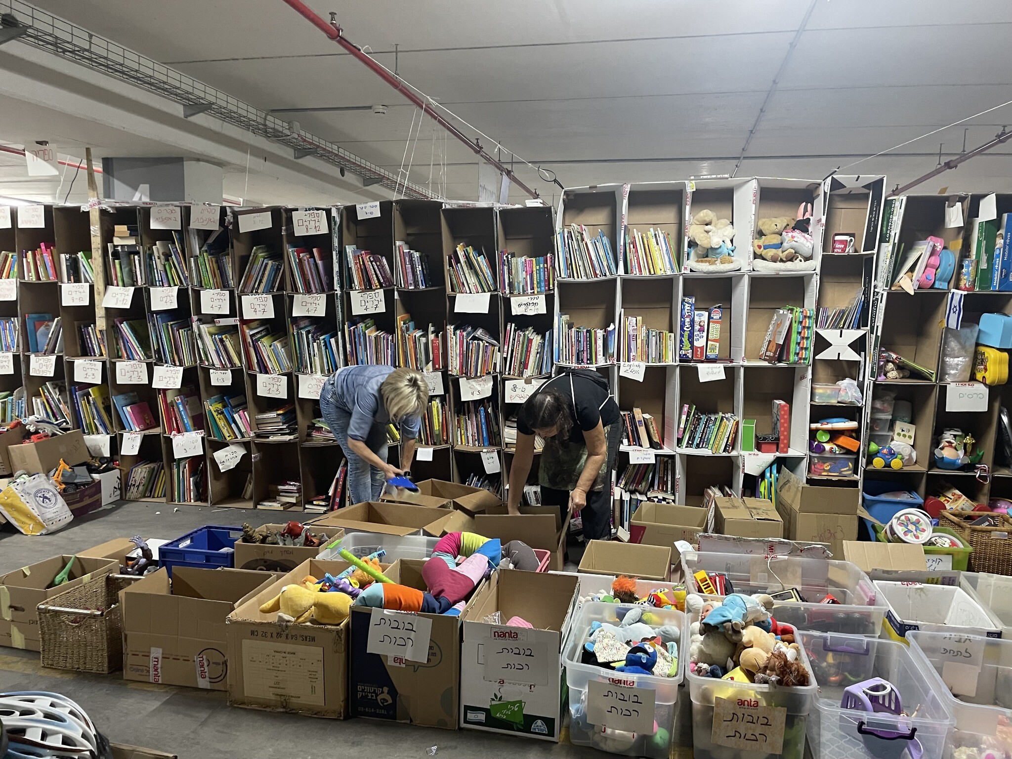 Des bénévoles aidant à trier et à emballer des livres et des jouets donnés au Centre d'opérations civiles, au centre de convention Expo Tel Aviv, le 19 octobre 2023. (Crédit : Sue Surkes/Times of Israel)