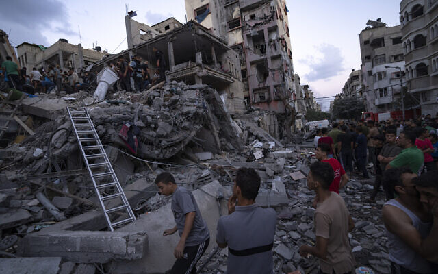 Des Palestiniens recherchent des blessés dans les décombres d’un bâtiment détruit suite à une frappe aérienne israélienne, le 10 octobre 2023. (Crédit : AP Photo/Fatima Shbair)