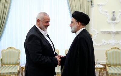 Le président iranien Ebrahim Raissi, à droite, salue le chef du groupe terroriste palestinien Hamas, Ismail Haniyeh au début de leur rencontre à son bureau à Téhéran, Iran, le 20 juin 2023. (Crédit : Bureau de la présidence iranienne/AP)