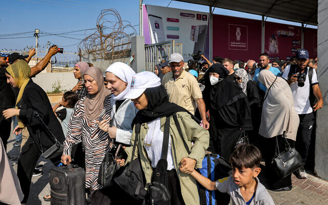 Des personnes traversent un portail pour entrer dans le poste frontière de Rafah vers l'Égypte, dans le sud de la bande de Gaza, le 1er novembre 2023. (Crédit : Mohammed ABED / AFP)