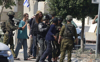 Des soldats israéliens retenant des résidents d'implantations après qu'ils ont pris d'assaut le village palestinien de Dayr Sharaf à la suite d'une attaque terroriste au cours de laquelle un conducteur israélien a été abattu, en Cisjordanie, le 2 novembre 2023. (Crédit : Jaafar Ashtiyeh/AFP)