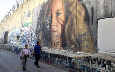 Des hommes passent devant une section de la barrière de sécurité d'Israël peinte d'un portrait de la détenue palestinienne Ahed Tamimi, le 6 novembre 2023 à Bethléem, en Cisjordanie. (Crédit : Hazem Bader / AFP) Des hommes passent devant une section de la barrière de sécurité d'Israël peinte d'un portrait de la détenue palestinienne Ahed Tamimi, le 6 novembre 2023 à Bethléem, en Cisjordanie. (Crédit : Hazem Bader / AFP)