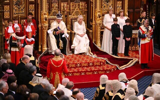 Le roi Charles III de Grande-Bretagne, portant la couronne d'État impériale et la robe d'État, est assis à côté de la reine Camilla de Grande-Bretagne, portant le diadème d'État de George IV, alors qu'il lit le discours du roi depuis le trône du souverain dans la chambre des Lords, lors de l'ouverture officielle du Parlement, aux Chambres du Parlement, à Londres, le 7 novembre 2023. (Crédit : Leon Neal / POOL / AFP)