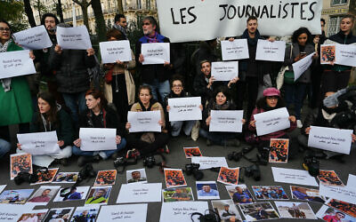 Des manifestants affichant les noms et les photos des journalistes qui ont été tués à Gaza depuis le début de la guerre entre Israël et le Hamas, près de la place de la République, à Paris, le 11 novembre 2023. (Crédit : Dimitar Dilkoff/AFP)
