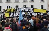 Des personnes tenant une banderole "Contre l'antisémitisme, les racismes et l'extrême-droite" participant à un rassemblement organisé par le parti La France Insoumise (LFI) pour une cérémonie de dépôt de gerbe en marge d'un rassemblement contre l'antisémitisme, au Square des Martyrs juifs du Vélodrome d'Hiver à Paris, le 12 novembre 2023. (Crédit : Geoffroy Van Der Hasselt/AFP)