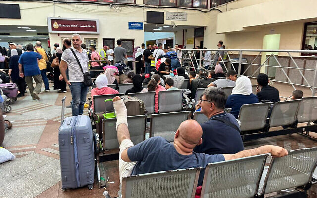 Des passagers évacuant la bande de Gaza arrivent dans la partie égyptienne du poste frontière de Rafah avec l'enclave côtière, le 12 novembre 2023, dans le cadre de la guerre entre Israël et le Hamas. (Crédit : AFP) Des passagers évacuant la bande de Gaza arrivent dans la partie égyptienne du poste frontière de Rafah avec l'enclave côtière, le 12 novembre 2023, dans le cadre de la guerre entre Israël et le Hamas. (Crédit : AFP)