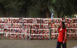 Photo d'illustration : une femme passe devant les portrait des israéliens pris en otage à Gaza après avoir été enlevés le 7 octobre pendant une manifestation pour leur libération à Tel Aviv, le 13 novembre 2023. (Crédit : Ahmad Gharabli/AFP)