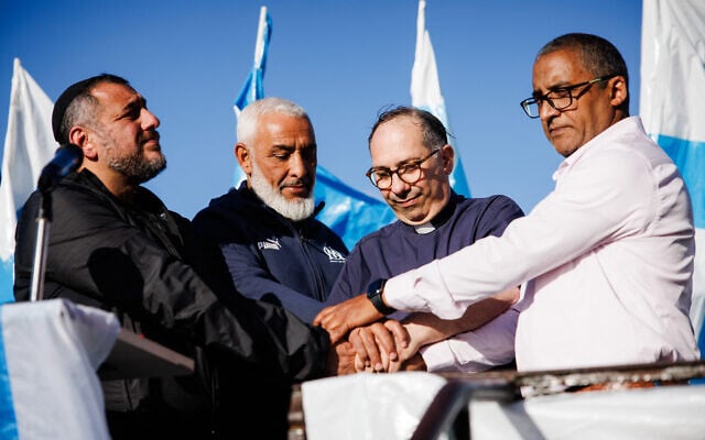 Le rabbin Haim Bendao (à gauche), Rachid Zeroual, leader du club des supporters de l'Olympique de Marseille (OM) South Winners (deuxième à gauche), le prêtre Olivier Spinosa (deuxième à droite), et l'imam Hassan Rajii (à droite), se tenant la main devant la basilique Notre-Dame de la Garde lors d'un rassemblement interreligieux pour la paix organisé par des chefs religieux juifs, musulmans et chrétiens, à Marseille, le 24 octobre 2023. (Crédit : CLEMENT MAHOUDEAU / AFP) Le rabbin Haim Bendao (à gauche), Rachid Zeroual, leader du club des supporters de l'Olympique de Marseille (OM) South Winners (deuxième à gauche), le prêtre Olivier Spinosa (deuxième à droite), et l'imam Hassan Rajii (à droite), se tenant la main devant la basilique Notre-Dame de la Garde lors d'un rassemblement interreligieux pour la paix organisé par des chefs religieux juifs, musulmans et chrétiens, à Marseille, le 24 octobre 2023. (Crédit : CLEMENT MAHOUDEAU / AFP)