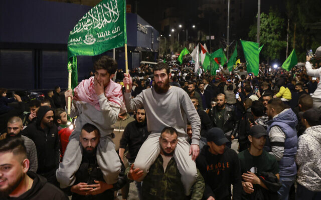 Des prisonniers palestiniens (portant des vêtements gris) brandissent des drapeaux du Hamas au milieu de leurs partisans après avoir été libérés des prisons israéliennes en échange d'otages innocents libérés par le Hamas de la bande de Gaza, à Ramallah, en Cisjordanie. (Crédit : Jaafar ASHTIYEH / AFP)