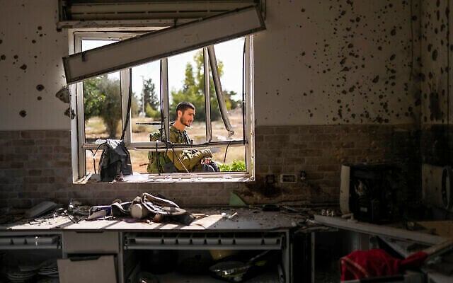 Un soldat israélien patrouille à côté d'une maison endommagée par des terroristes du Hamas dans l'enceinte du kibboutz Kissufim, dans le sud d'Israël, le 21 octobre 2023. (Crédit : AP/Francisco Seco)