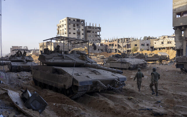 Les troupes de l'armée israélienne à côté d'un immeuble détruit pendant l'opération terrestre dans la bande de Gaza, le 8 novembre 2023. (Crédit : AP Photo/Ohad Zwigenberg) Les troupes de l'armée israélienne à côté d'un immeuble détruit pendant l'opération terrestre dans la bande de Gaza, le 8 novembre 2023. (Crédit : AP Photo/Ohad Zwigenberg)