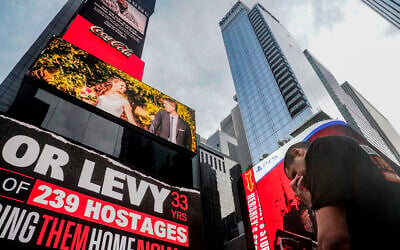 Michael Levy baissant la tête sous le coup de l'émotion après le dévoilement d'un panneau d'affichage numérique à Times Square montrant les affiches des otages du Hamas pris par les terroristes, dont son frère aîné Or Levy, lors de l'assaut du 7 octobre contre Israël, le 17 novembre 2023, à New York. (Crédit : Bebeto Matthews/AP Photo)