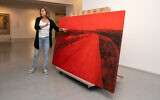 L'artiste Ziva Jelin avec son tableau "Curving Road", endommagé lors de l'attaque du 7 octobre 2023 par des terroristes du Hamas au kibboutz Beeri, avant qu'il ne soit temporairement accroché au musée d'Israël, en novembre 2023 (Crédit : Zohar Shemesh)