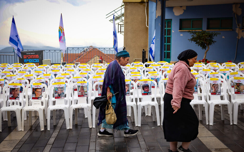 Des gens passant devant des chaises vides avec des photos de civils pris en otage par les terroristes du Hamas à Gaza, dans la ville de Safed, au nord du pays, le 14 novembre 2023. (Crédit : David Cohen/Flash90)