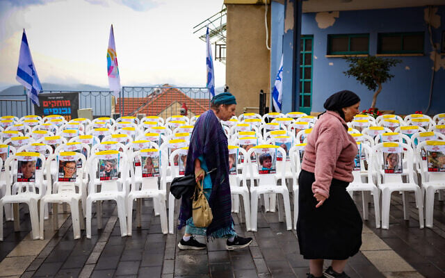 Des gens passant devant des chaises vides avec des photos de civils pris en otage par les terroristes du Hamas à Gaza, dans la ville de Safed, au nord du pays, le 14 novembre 2023. (Crédit : David Cohen/Flash90)