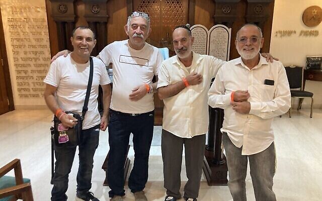 Quatre hommes de Sderot montrent les bracelets qui les identifient comme des personnes évacuées, après les prières du soir, à l'Hôtel Royal de la mer Morte, le 30 octobre 2023. (Crédit : Mati Wagner/Times of Israël)