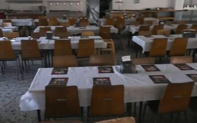 Une table dressée dans la salle à manger du kibboutz Nir Oz avec des affiches des personnes assassinées et enlevées lors du massacre du 7 octobre par le Hamas, le 14 novembre 2023. (Crédit : Capture d'écran de la Douzième chaîne ; utilisée conformément à l'article 27a de la loi sur le droit d'auteur) Une table dressée dans la salle à manger du kibboutz Nir Oz avec des affiches des personnes assassinées et enlevées lors du massacre du 7 octobre par le Hamas, le 14 novembre 2023. (Crédit : Capture d'écran de la Douzième chaîne ; utilisée conformément à l'article 27a de la loi sur le droit d'auteur)