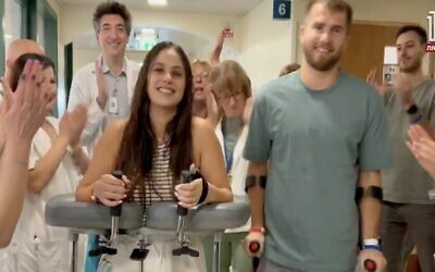 Gali Segal et Ben Binyamin marchant dans un hôpital où ils sont en rééducation après avoir perdu chacun leur jambe droite lors du pogrom du 7 octobre, dans une vidéo diffusée par la Douzième chaîne, le 17 novembre 2023. (Crédit : Capture d'écran de la Douzième chaîne)