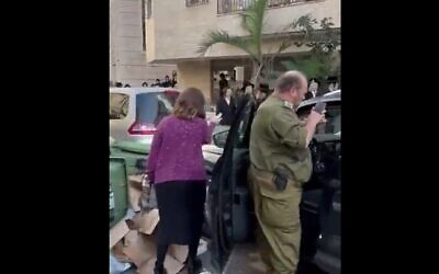 Un soldat réserviste haredi, à droite, pris à partie par des extrémistes ultra-orthodoxes dans la ville de Bnei Brak, le 20 novembre 2023. (Crédit : Capture d'écran d'une vidéo Twitter : utilisée conformément à l'article 27a de la loi sur le droit d'auteur)