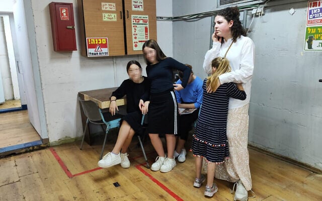 Un élève d'une famille d'accueil Alumim reçoit un câlin d'un enseignant alors qu'il attend dans un abri antiatomique dans le village de jeunes Or Simcha, à Kfar Habad, dans le centre d'Israël, le 26 octobre 2023. (Crédit : Gavriel Fiske/Times of Israel)