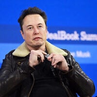 Elon Musk montrant une plaque militaire symbolique portée en l'honneur des otages israéliens sur scène lors du New York Times Dealbook Summit 2023, au Jazz at Lincoln Center, à New York, le 29 novembre 2023. (Crédit : Slaven Vlasic/Getty Images via AFP)