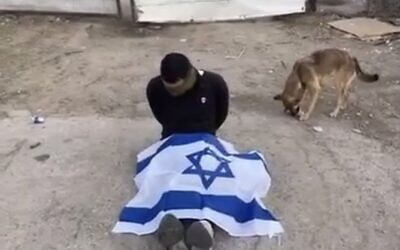 Un détenu palestinien, les yeux bandés, forcés de s'asseoir avec un drapeau israélien sur les jambes, en Cisjordanie, le 31 octobre 2023 ou quelques jours auparavant. (Capture d'écran : X)