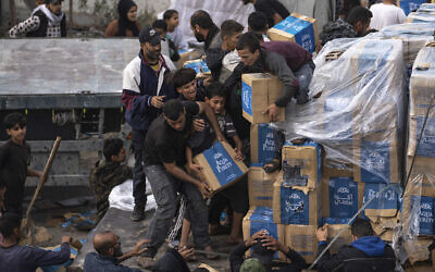 Des Gazaouis pillant un camion d'aide humanitaire alors qu'il pénètre dans la bande de Gaza à Rafah, le 17 décembre 2023. (Crédit : Fatima Shbair/AP)