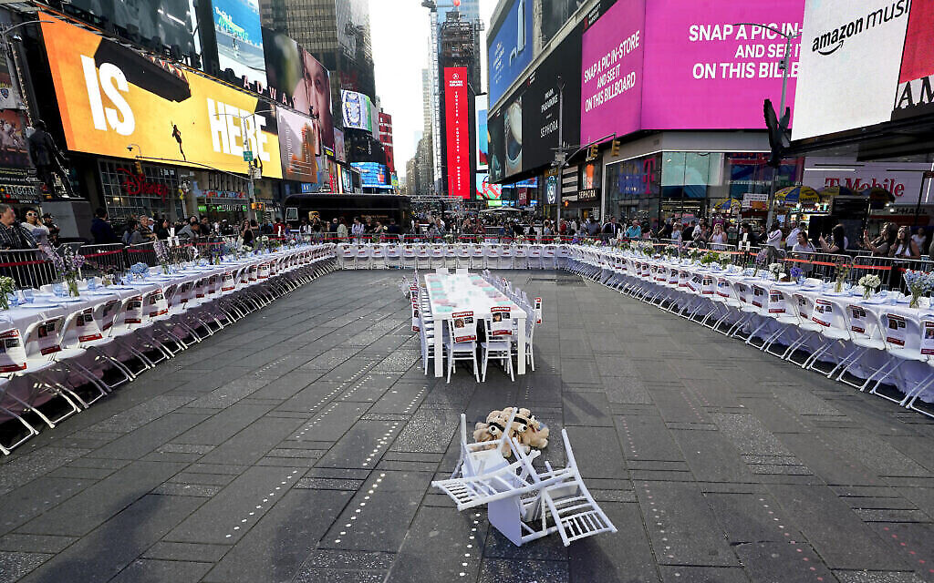 Le Conseil israélo-américain, le Comité juif américain et d'autres organisations juives dévoilent une installation à Times Square, le 26 octobre 2023, fait d'une table de Shabbat de 222 couverts avec une chaise et une assiette pour chacun des otages du Hamas. (Crédit : TIMOTHY A. CLARY / AFP) Le Conseil israélo-américain, le Comité juif américain et d'autres organisations juives dévoilent une installation à Times Square, le 26 octobre 2023, fait d'une table de Shabbat de 222 couverts avec une chaise et une assiette pour chacun des otages du Hamas. (Crédit : TIMOTHY A. CLARY / AFP)
