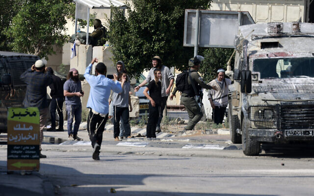 Des soldats israéliens se confrontant à des résidents de l'implantation d'Einav qui tentent d'attaquer la ville de Deir Sharaf, dans le gouvernorat de Naplouse,  suite à un attentat terroriste qui a tué un conducteur israélien au volant de sa voiture, le 2 novembre 2023. (Crédit : Jaafar Ashtiyeh/AFP)