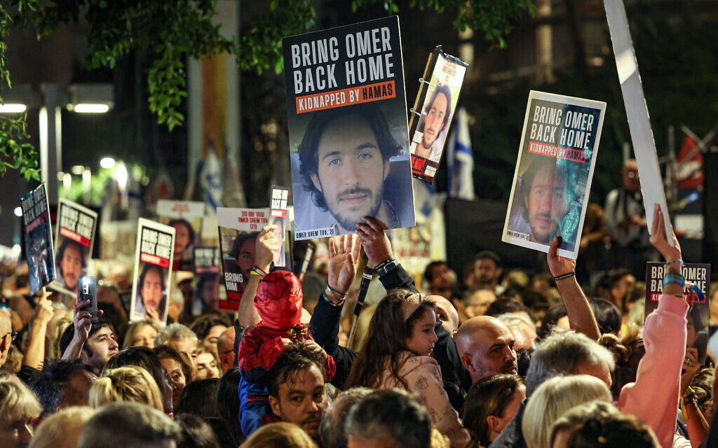 Des manifestants avec la photo d'Omer Shem Tov, 21 ans, pendant un rassemblement pour la libération des otages retenus à Gaza depuis l'attaque du 7 octobre, à Tel Aviv, le 2 décembre 2023. (Crédit : Ahmad Gharabli/AFP) Des manifestants avec la photo d'Omer Shem Tov, 21 ans, pendant un rassemblement pour la libération des otages retenus à Gaza depuis l'attaque du 7 octobre, à Tel Aviv, le 2 décembre 2023. (Crédit : Ahmad Gharabli/AFP)