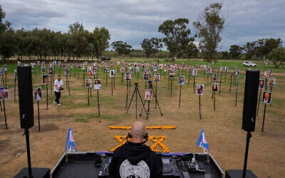 Les photos des personnes tuées et retenues en captivité par les terroristes du Hamas pendant leur attaque de la rave-party Supernova, dans le sud d'Israël, affichées sur le site même d'événement alors que des DJ israéliens passent de la musique en commémoration du massacre du 7 octobre à proximité du kibboutz Reim, le 28 novembre 2023. (Crédit : AP Photo/Ohad Zwigenberg)