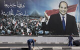 Des travailleurs nettoient les rues sous un panneau d’affichage soutenant le président égyptien Abdel Fattah el-Sissi pour les élections présidentielles, au Caire, en Égypte, le 10 décembre 2023. (Crédit : Amr Nabil/AP)