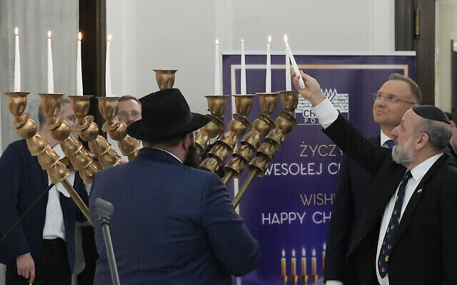 Des députés, le président Andrzej Duda, deuxième à droite, et des membres de la communauté juive polonaise pour l'allumage des bougies lors de la dernière nuit de Hanoukka au parlement de Varsovie, en Pologne, le jeudi 14 décembre 2023. (Crédit : AP/Czarek Sokolowski) Des députés, le président Andrzej Duda, deuxième à droite, et des membres de la communauté juive polonaise pour l'allumage des bougies lors de la dernière nuit de Hanoukka au parlement de Varsovie, en Pologne, le jeudi 14 décembre 2023. (Crédit : AP/Czarek Sokolowski)